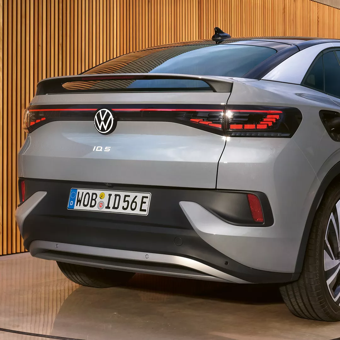 VW ID.5 in grau steht vor einer Garage und wird an ID. Charger geladen