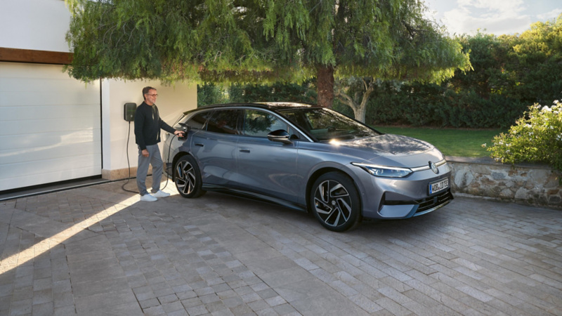 Un homme branche la prise de chargement de sa Volkswagen ID.7 Tourer.