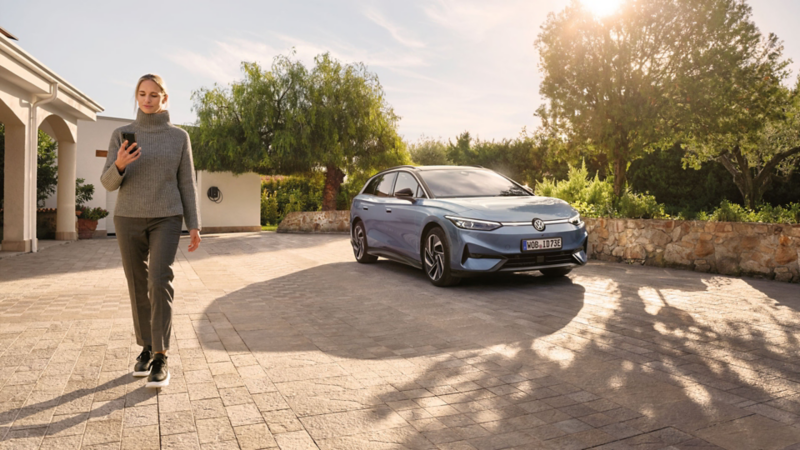 Une femme s'éloigne de l'ID.7 Tourer stationnée dans une cour.