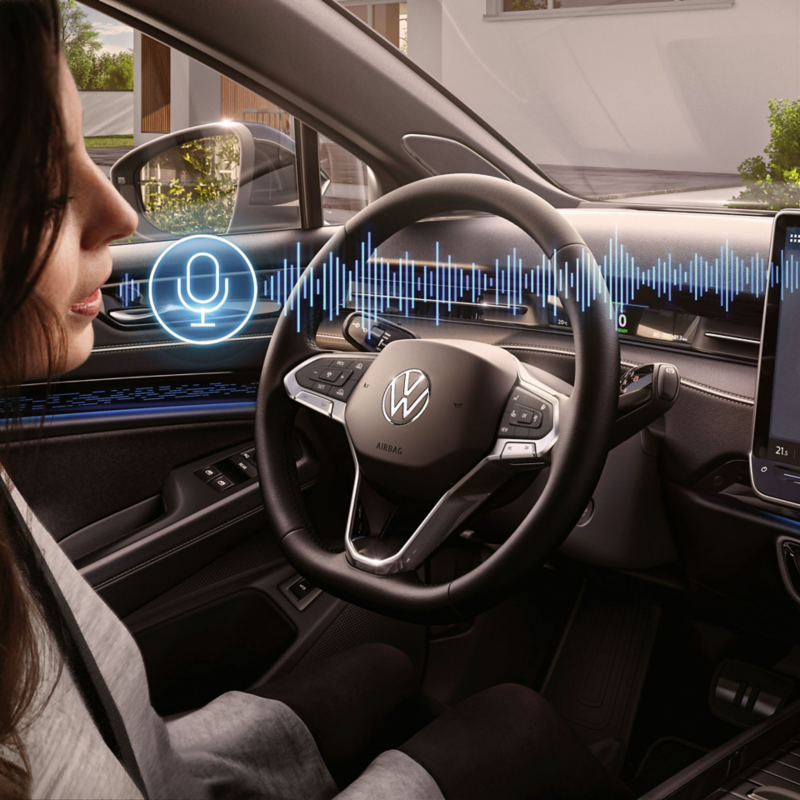 A woman sits in the driver's seat in the VW ID.7 and talks to the language assistant.