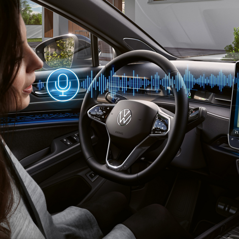A woman sits in the driver's seat in the VW ID.7 and talks to the language assistant.