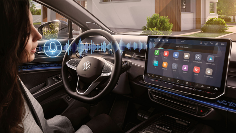 A woman sits in the driver’s seat in a VW ID.7 and uses the voice assistant.