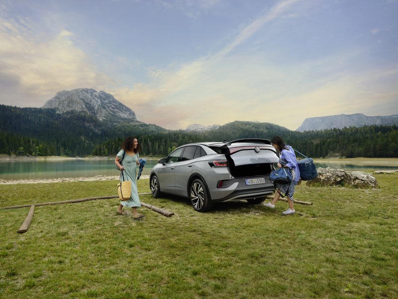 ID.5 parked on grass with a mountain backdrop. Two friends are packing up camping gear.