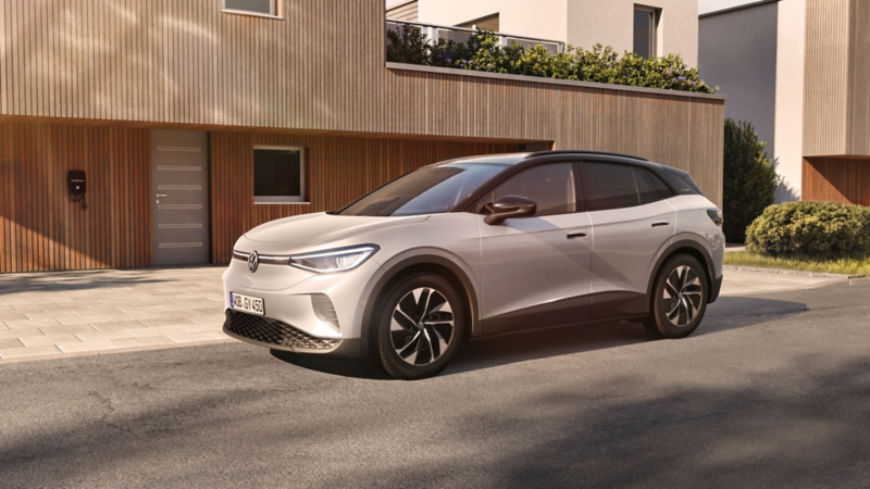 VW ID.4 ENERGY steht vor einem Haus mit Holzfassade und Wallbox an der Wand.