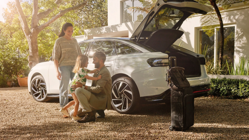 Eine Familie steht vor einem VW ID.7 mit geöffnetem Kofferraum.