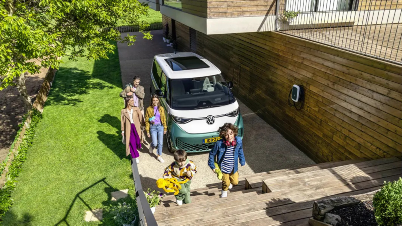 ID. Buzz staat op de oprit, een familie is net uitgestapt en loopt via een trap naar een huis