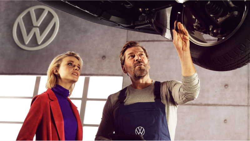 A woman and a man look at the underbody during the repair.