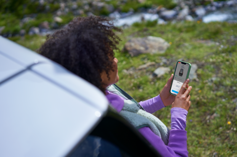Un hombre usando el teléfono móvil, apoyado en la ventanilla de un vehículo VW.