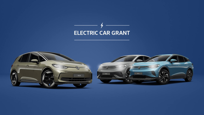 Three Volkswagen electric cars on display against a blue background with the text "Electric Car Grant" above, emphasizing eco-friendly innovation.