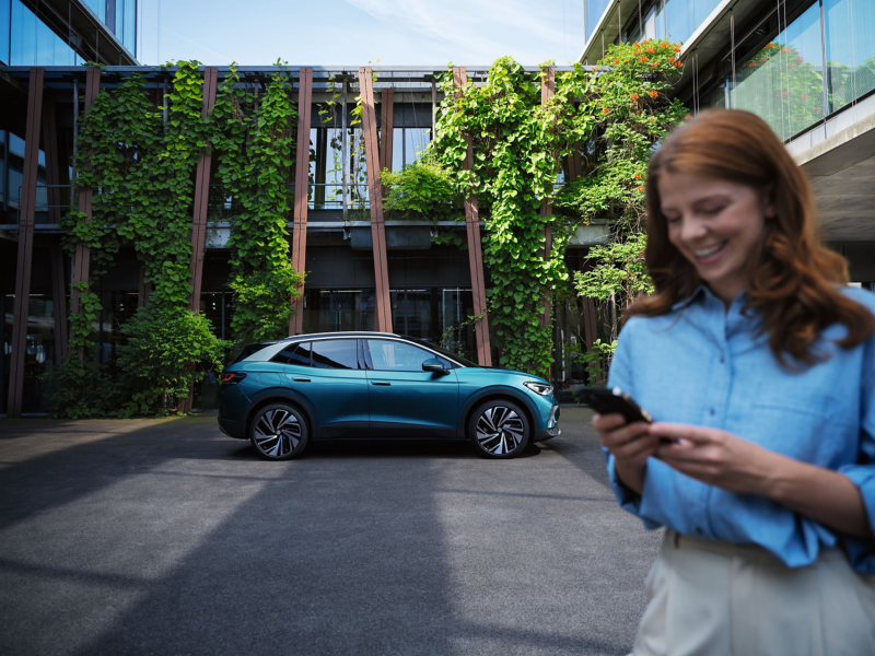 Woman standing at front of frame with VW electric car in background