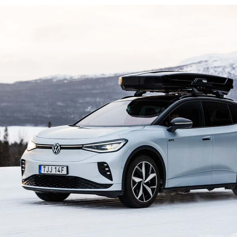 En vit ID.4 med takbox parkerad i vinterlandskap med ett fjäll i bakgrunden