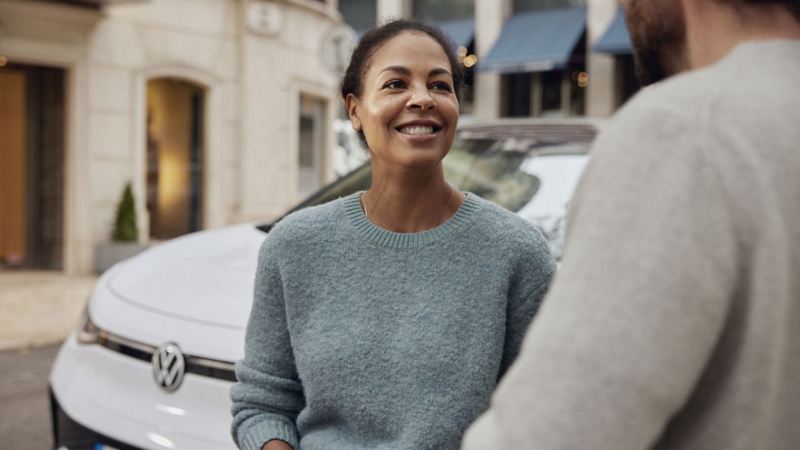 Una donna in piedi accanto alla sua VW Golf bianca sulla strada
