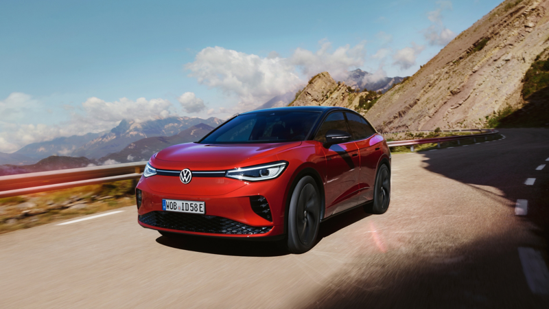 A red VW ID.5 being driven on a road with mountains in the background