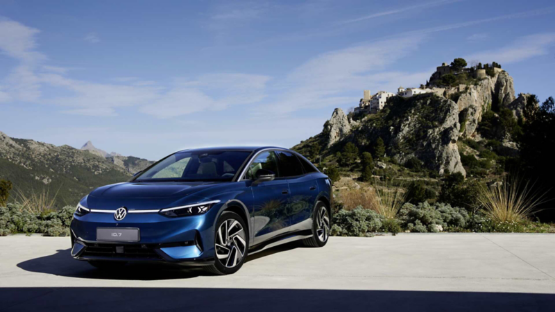 Volkswagen ID.7 en color azul, cerca de paisaje montañoso con cielo azul.