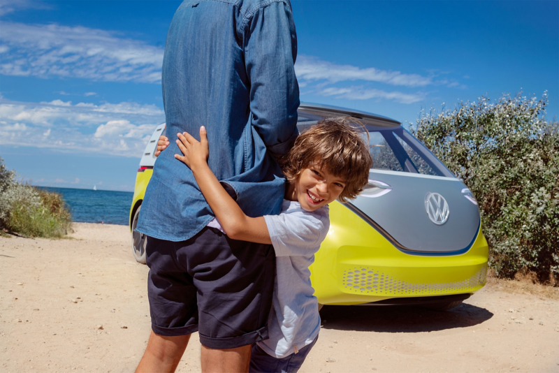 Boy facing camera with yellow VW behind