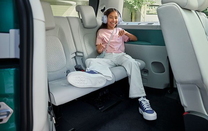 Girl in back seat of ID.Buzz listening to music