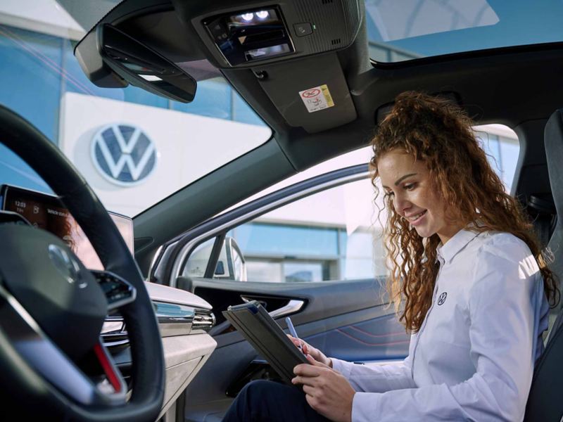 Vista di un addetto Volkswagen seduto all'interno di un'auto mentre esegue un'ispezione del veicolo.
