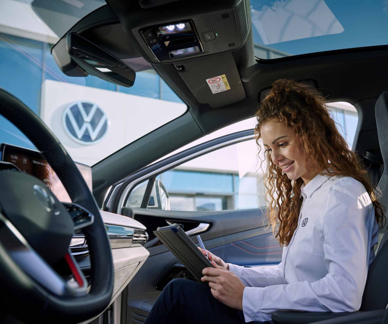 Vista di un addetto Volkswagen seduto all'interno di un'auto mentre esegue un'ispezione del veicolo.