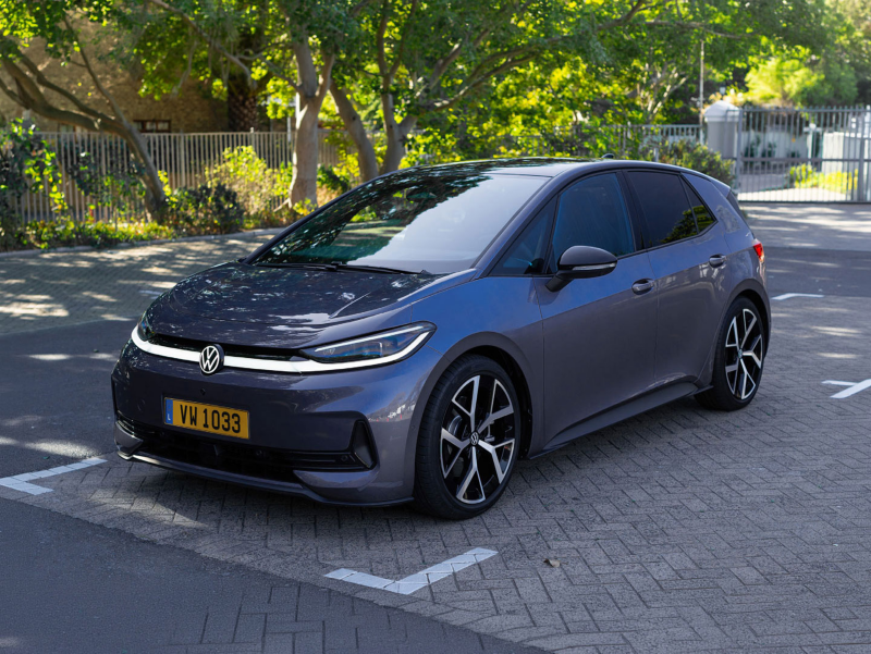 Volkswagen ID.3 Neo Life gris stationnée sur une place de parking, entourée d’arbres dans un environnement urbain calme.