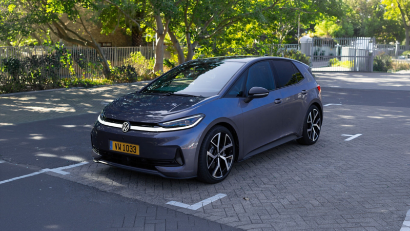 Volkswagen ID.3 Neo Life gris stationnée sur une place de parking, entourée d’arbres dans un environnement urbain calme.