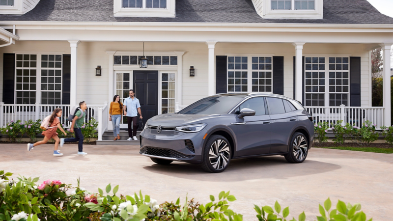 A family approaches a 2024 VW ID.4 parked in the drive way.