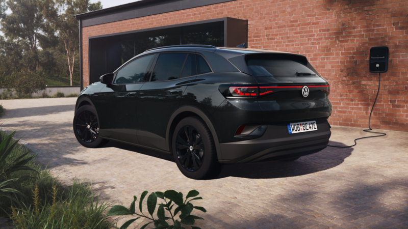 Ein VW ID.4 Black Edition in Heckansicht steht seitlich vor einem modernen Haus.