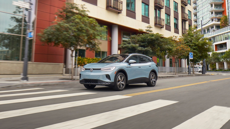 A grey 2024 VW ID.4 driving down a road in an urban city