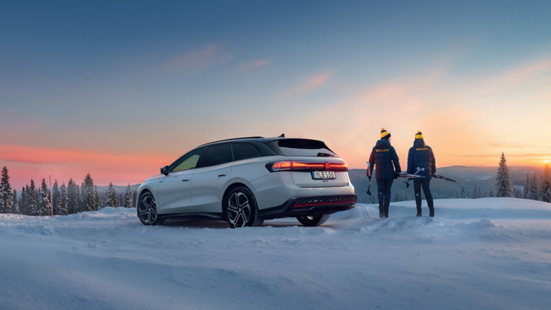 En vit ID.7 Tourer i vinterlandskap, två skidåkare går från bilen