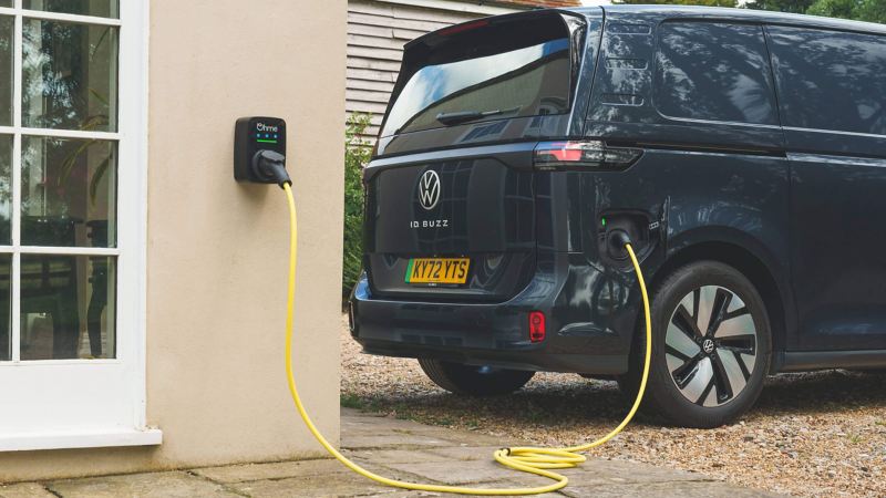 Photo showing an ID. Buzz parked at a house with the charging cable plugged in. 