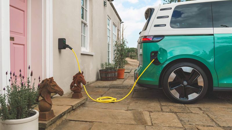 a teal ID.Buzz parked and plugged into an home charger