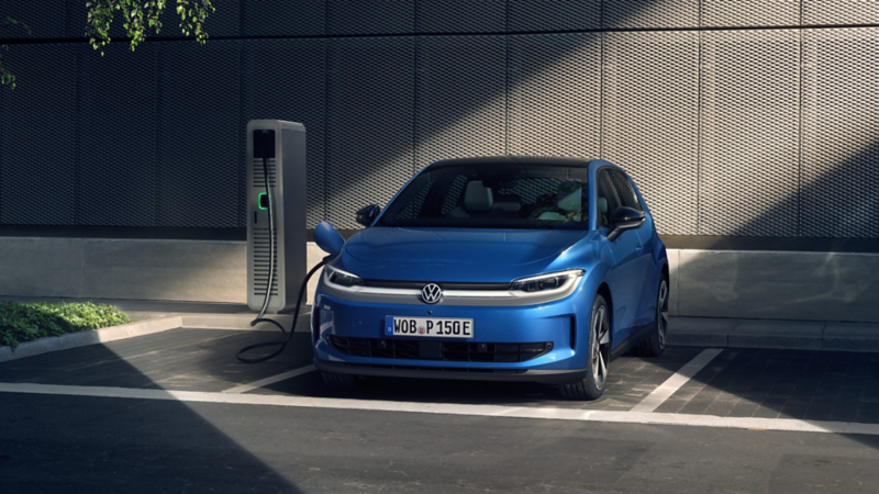 Ein blauer VW ID. Polo steht an einer Ladesäule auf einem Parkplatz und lädt.