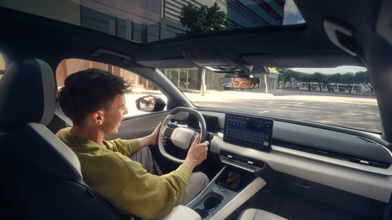 A woman is sitting in the driver's seat of a blue VW ID. Polo and reaches for a bouquet of flowers on the passenger seat.