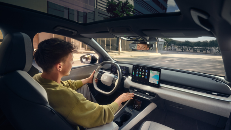  Vue intérieure du tableau de bord d'une Volkswagen ID. Polo, avec un grand écran de navigation au centre et un petit tableau de bord numérique derrière le volant. 
