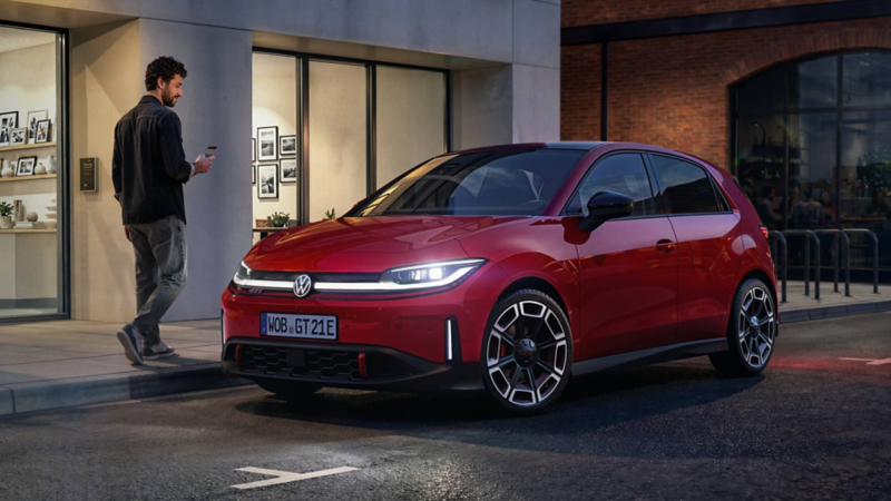 A person walks past a red VW ID. Polo GTI parked in front of a modern building.