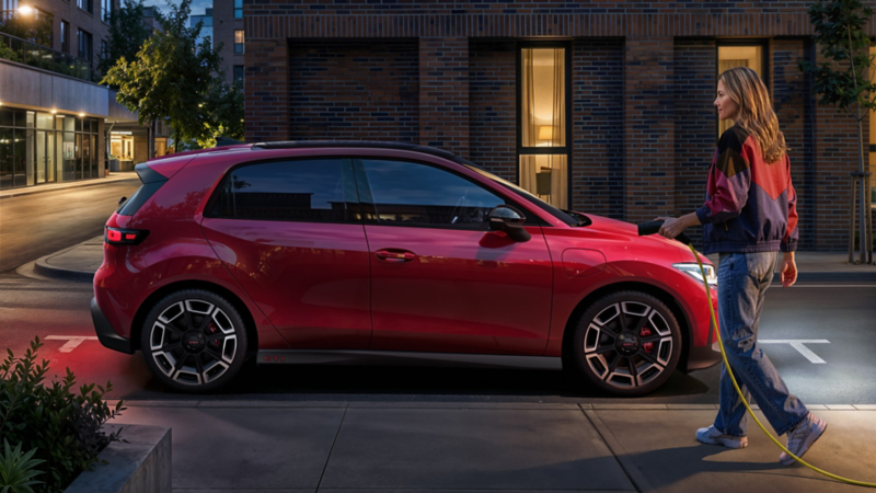 Une VW ID. Polo GTI rouge est garée et une femme s'apprête à la brancher.