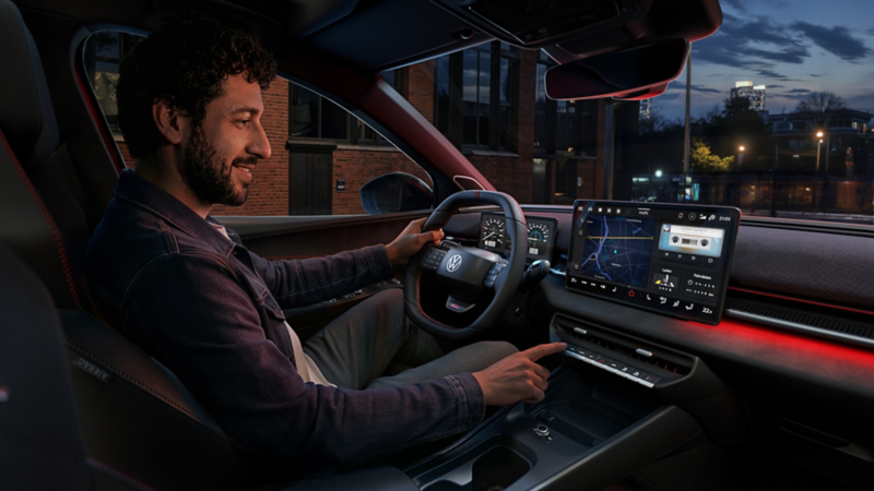 A person operates a button on the infotainment system in the VW ID. Polo GTI.