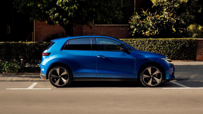 Ein blauer VW ID. Polo fährt auf einer Straße mit Bäumen im Hintergrund.