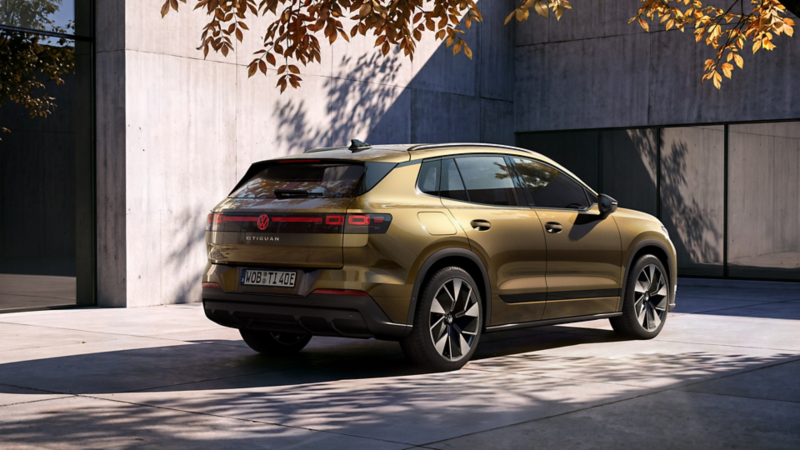 En oliven-bronzefarvet VW ID. Tiguan set skråt bagfra holder parkeret foran en moderne bygning.