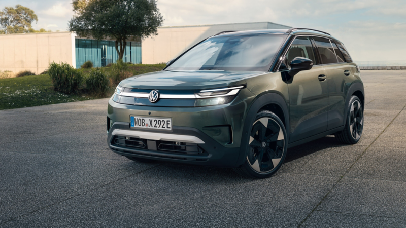 Un VW ID. Cross vert est garé sur une surface en béton devant un bâtiment moderne en verre.
