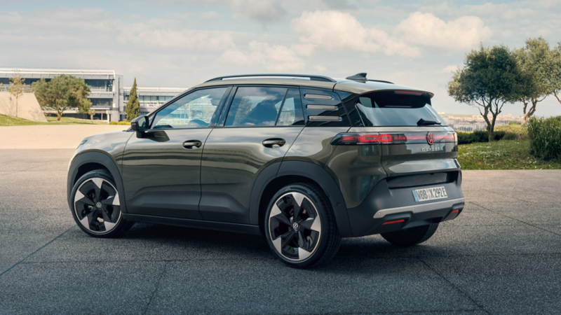 Vyn bakifrån av en grön VW ID. Cross som står parkerad på ett torg omgivet av gröna träd.