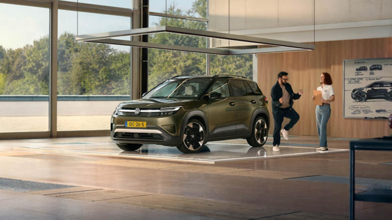 Een enthousiaste man praat met een vrouwelijke ingenieur naast een Volkswagen ID. Cross.