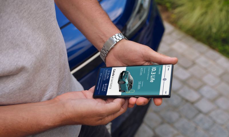 Un uomo tiene tra le mani uno smartphone con la schermata sul simulatore dei costi e dei tempi di ricarica di Volkswagen ID.3
