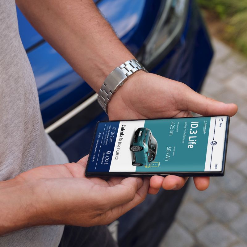 Un uomo tiene tra le mani uno smartphone con la schermata sul simulatore dei costi e dei tempi di ricarica di Volkswagen ID.3