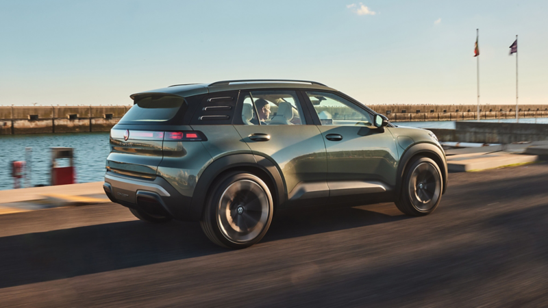 Vue de trois quarts arrière d’une VW ID. CROSS Concept verte roulant sur une route côtière.
