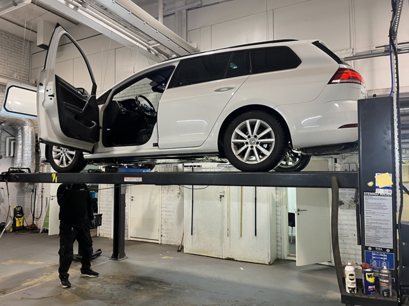 En vit Volkswagen är upphissad under en bilbesiktning