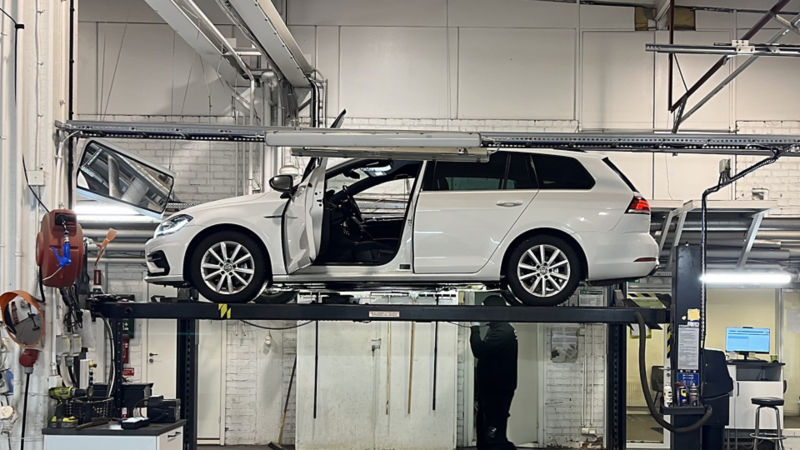 En vit Volkswagen står upphissad under en bilbesiktning