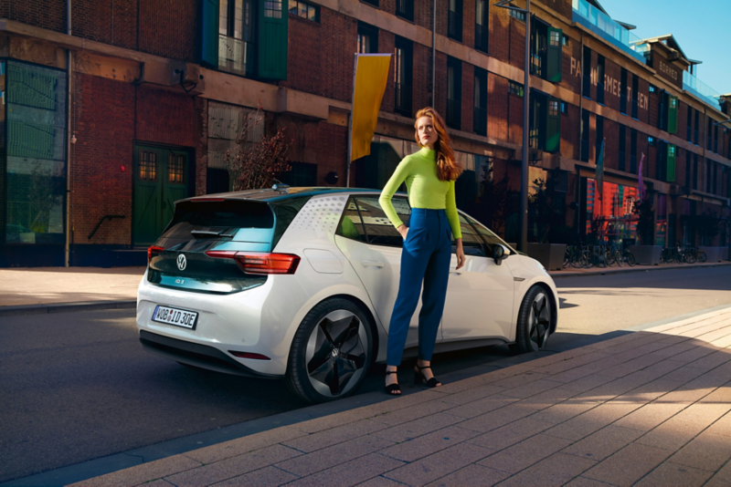 Kvinde står foran en hvid ID.3 der er parkeret ved en kantsten