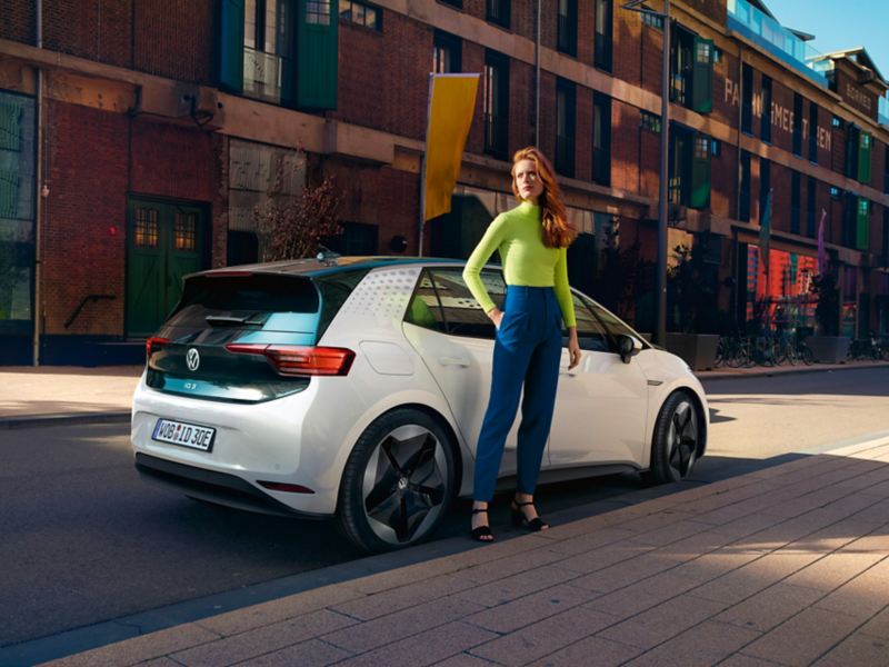 Véhicule Volkswagen ID.3 garée sur un place de parking avec une femme à côté