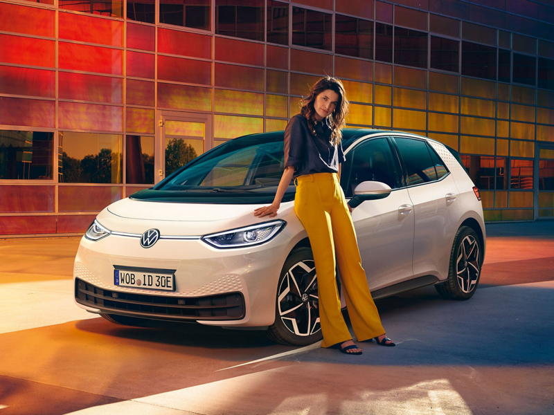 Eine Frau lehnt an einem VW ID. 3.