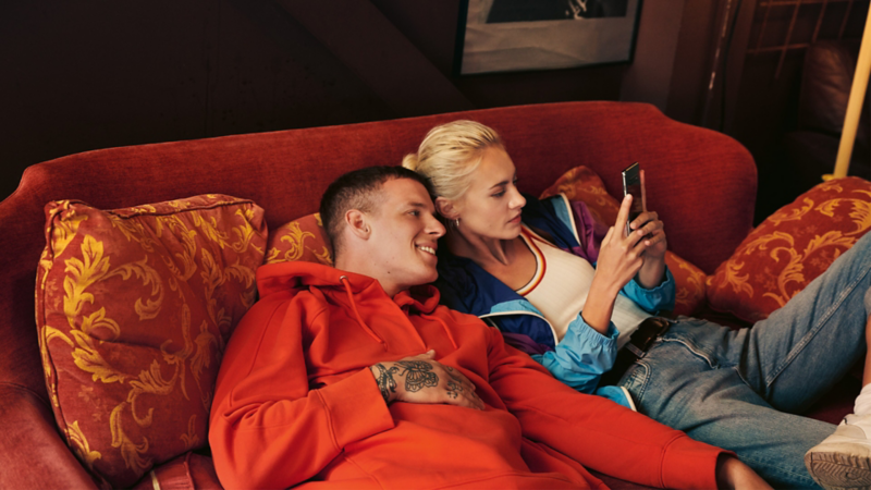 Et par ligger sammen i en sofa og kigger på en mobil